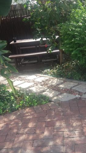 a park bench sitting on a brick walk way at Pennylane Guest House in Ermelo