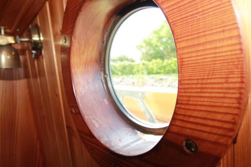 a round window in a wooden door with a mirror at Boat and Breakfast in Strijensas