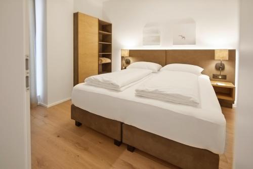 a bedroom with a large bed with white sheets at Hotel Gösser Bräu in Wels