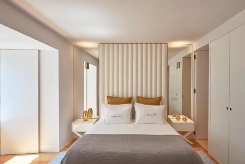 um quarto com uma grande cama branca com almofadas brancas em My Lisbon Home- Chiado em Lisboa