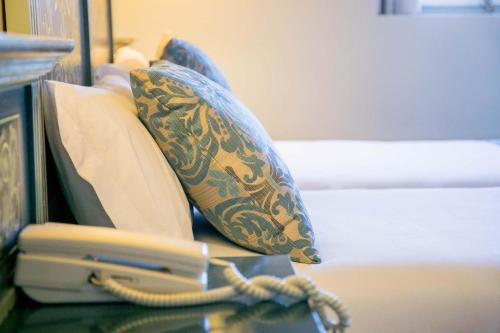 a bed with pillows and a phone on a table at Palacio de los Velada in Avila