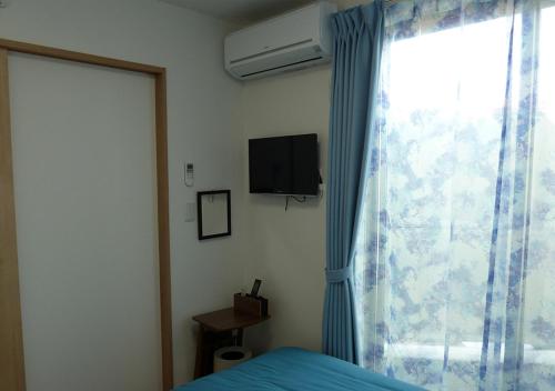 a bedroom with a bed and a window with a television at Kanaloa Funabashi in Funabashi