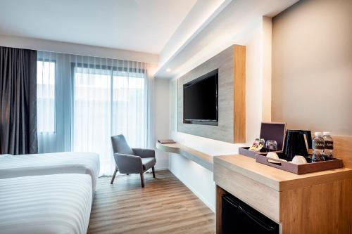 a hotel room with a bed and a television at Hotel Amber Pattaya in Pattaya Central