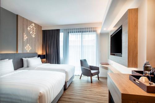 a hotel room with two beds and a television at Hotel Amber Pattaya in Pattaya Central