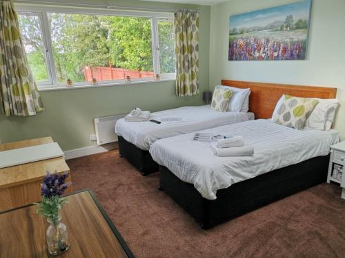 two beds in a room with two windows at Chalet Cottages in Streatley