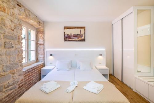 a bedroom with a bed and a brick wall at Idassa Atrium rooms in Zadar