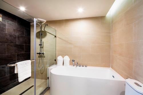 a bathroom with a bath tub and a shower at Hotel Amber Pattaya in Pattaya Central