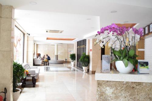 un vestíbulo con flores púrpuras en un jarrón blanco en Rang Dong Hotel, en Ho Chi Minh
