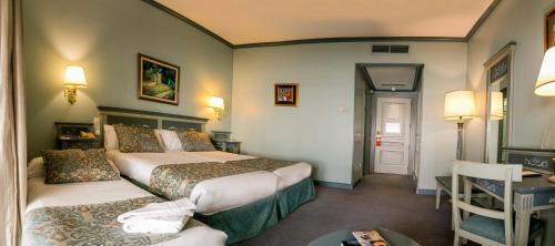 a hotel room with two beds and a table at Palacio de los Velada in Avila