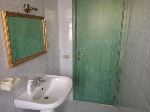 a bathroom with a sink and a green door at Sunny garden house in Villasimius