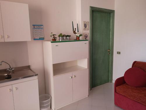 a kitchen with a green door next to a room at Sunny garden house in Villasimius