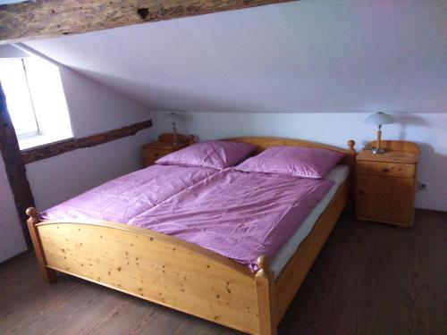 ein Schlafzimmer mit einem Holzbett mit violetter Bettwäsche in der Unterkunft Jurahaus Maisonette Wohnung in Solnhofen