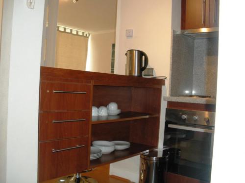 a kitchen with a wooden cabinet with dishes in it at Departamentos Pontoni in Santiago