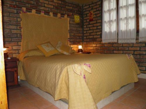 a bedroom with a large bed in a brick wall at Cabañas Tierra del Sol Aldea de Montaña in Los Árboles