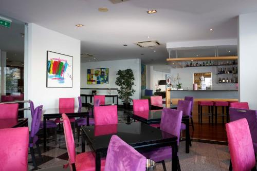 a restaurant with pink chairs and tables and a bar at Madeira Regency Cliff - Adults Only in Funchal