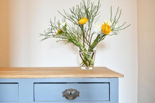 a vase of flowers sitting on top of a dresser at Gästehaus & Café Leeze in Bad Dürkheim