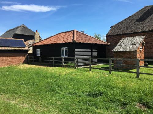 a black house with a wooden fence in a yard at The Stables Kings Ripton in Huntingdon