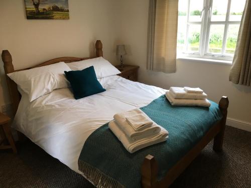 een slaapkamer met een bed met twee handdoeken erop bij The Stables Kings Ripton in Huntingdon