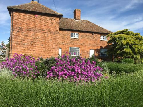 a brick house with purple flowers in front of it at The Stables Kings Ripton in Huntingdon