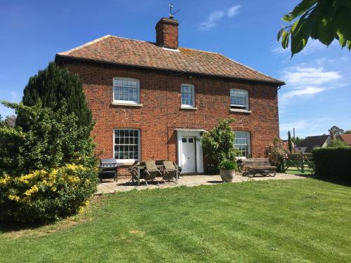 a large brick house with chairs in the yard at The Stables Kings Ripton in Huntingdon