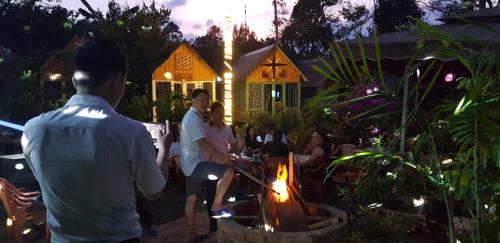 a group of people standing around a fire in a yard at Garden Homestay in Di Linh
