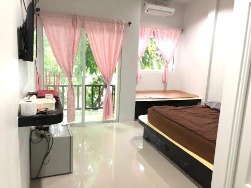 a bedroom with a bed and a window with pink curtains at chillchillsangkhlaburi โรงแรมชิลชิลสังขละบุรี in Sangkhla Buri