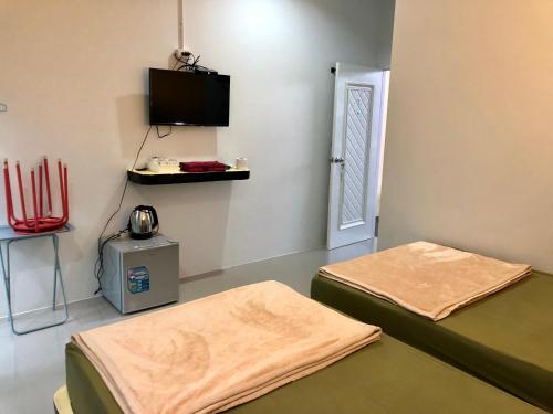 a room with two beds and a flat screen tv at chillchillsangkhlaburi โรงแรมชิลชิลสังขละบุรี in Sangkhla Buri