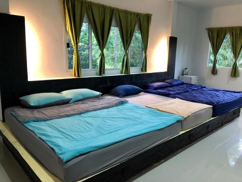 two twin beds in a bedroom with windows at chillchillsangkhlaburi โรงแรมชิลชิลสังขละบุรี in Sangkhla Buri