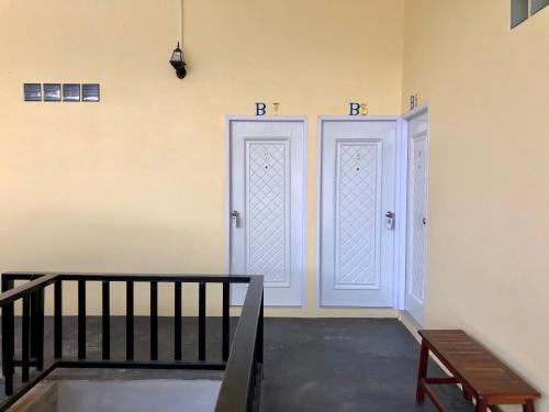 two white doors in a room with a staircase at chillchillsangkhlaburi โรงแรมชิลชิลสังขละบุรี in Sangkhla Buri