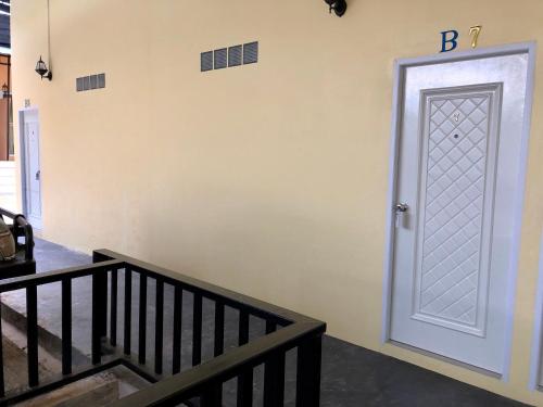 a white door with a letter b on a wall at chillchillsangkhlaburi โรงแรมชิลชิลสังขละบุรี in Sangkhla Buri