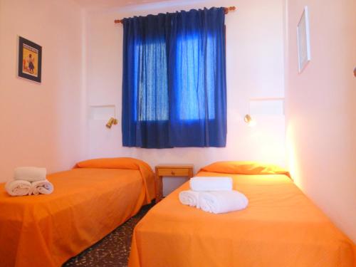 2 camas naranjas en una habitación con ventana azul en Rentalmar El Capitan en Hospitalet de l'Infant