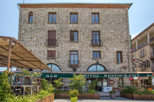 a large brick building with a sign for a bar at Hôtel de la Citadelle in Sisteron
