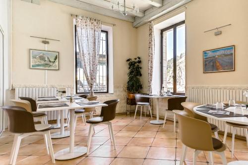 a restaurant with tables and chairs and windows at Hôtel de la Citadelle in Sisteron