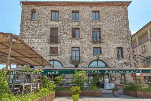 a large brick building with a sign for a bar at Hôtel de la Citadelle in Sisteron