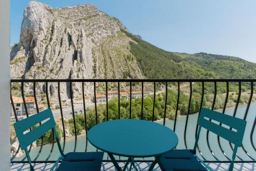 a table and chairs on a balcony with a mountain at Hôtel de la Citadelle in Sisteron