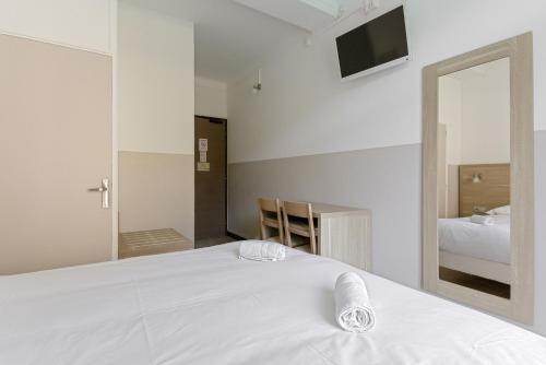 a bedroom with a large white bed and a mirror at Hôtel de la Citadelle in Sisteron