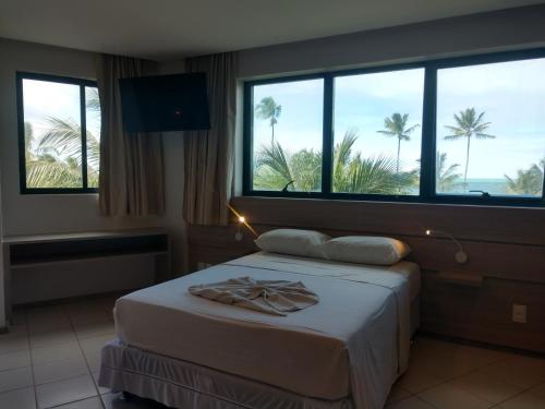 a bedroom with a bed with a view of palm trees at MARULHOS RESORT - STÚDIOS TEMPORADA in Porto De Galinhas