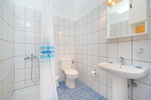 a white bathroom with a toilet and a sink at Hotel Anna in Skala Potamias