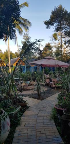 a brick walkway with tables and umbrellas in a garden at Garden Homestay in Di Linh