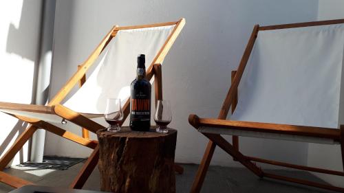 a bottle of wine sitting on a stump with two glasses at TMB (Train / Metro& Bus ) Oporto Station House in Porto