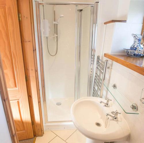 a white bathroom with a shower and a sink at Tryfan Holiday Cottage in Llanfairpwllgwyngyll