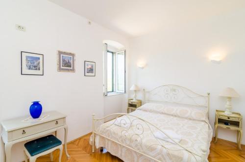 a white bedroom with a bed and a desk and a window at Stone House DiMaTo in Gruda