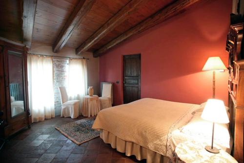 a bedroom with a white bed and a red wall at Dindina Agriturismo in Neviglie