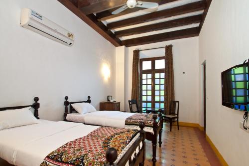 a bedroom with two beds and a tv and a window at Hospedaria Abrigo De Botelho in Panaji