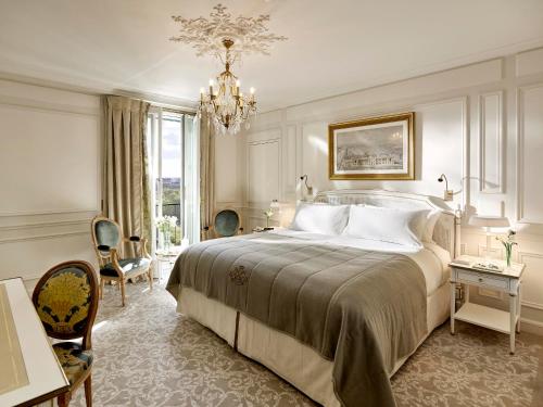 a bedroom with a large bed and a chandelier at Le Meurice – Dorchester Collection in Paris