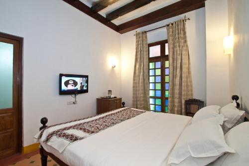 a bedroom with a white bed and a tv on the wall at Hospedaria Abrigo De Botelho in Panaji