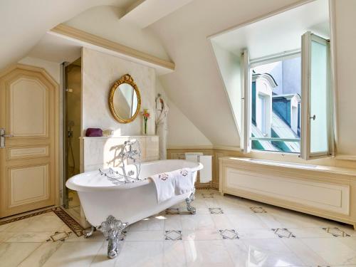 a bathroom with a tub and a large window at Le Meurice – Dorchester Collection in Paris