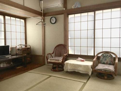 a room with two chairs and a table and a clock at kyoka house練馬 in Tokyo