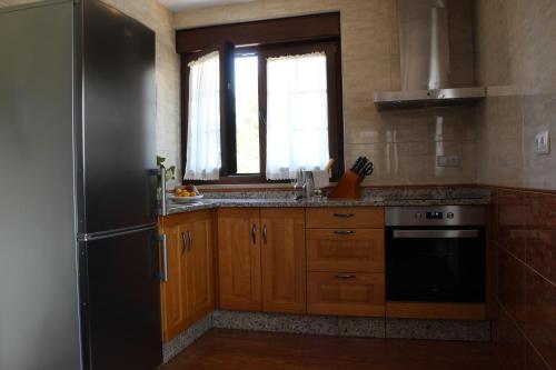 a kitchen with wooden cabinets and a black refrigerator at Apartamentos rurales la Aguilera in Oviñana