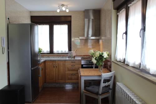 a kitchen with a table with a vase of flowers on it at Apartamentos rurales la Aguilera in Oviñana